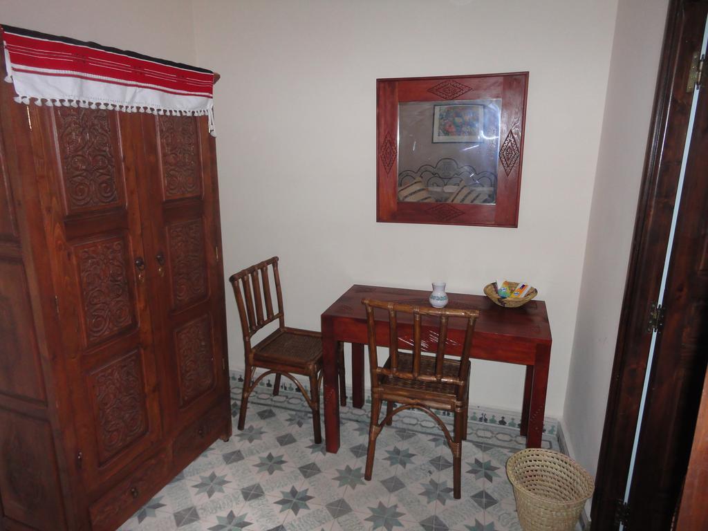 Armoire en bois sculpté et bureau dans une chambre du riad