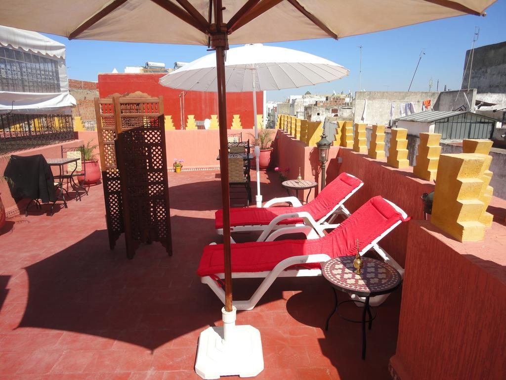 Terrasse du Riad Dar Yanis avec transats et parasols sur les toits de la médina